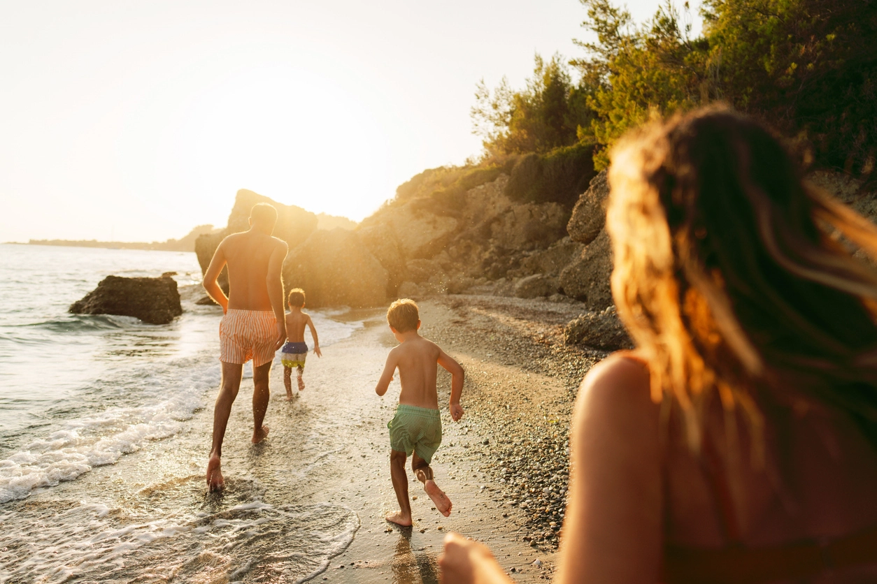 Familie rennt am Kieselstrand im Sonnenuntergang