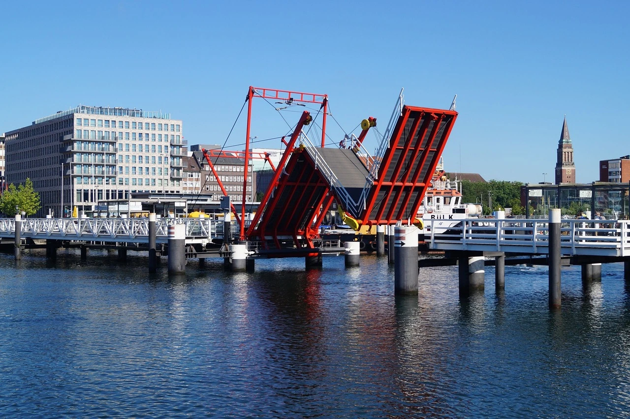 Rote Zugbrücke über Gewässer in Bewegung vor Häuserfassade