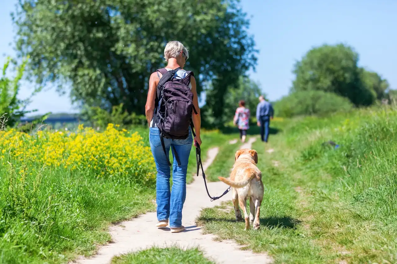 Frau geht mit ihrem Hund an der Leine spazieren