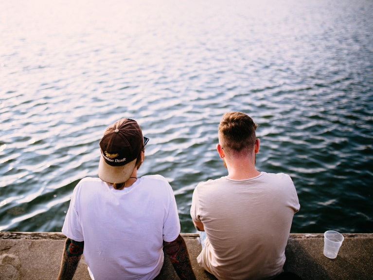 Zwei Männer sitzen am Wasser