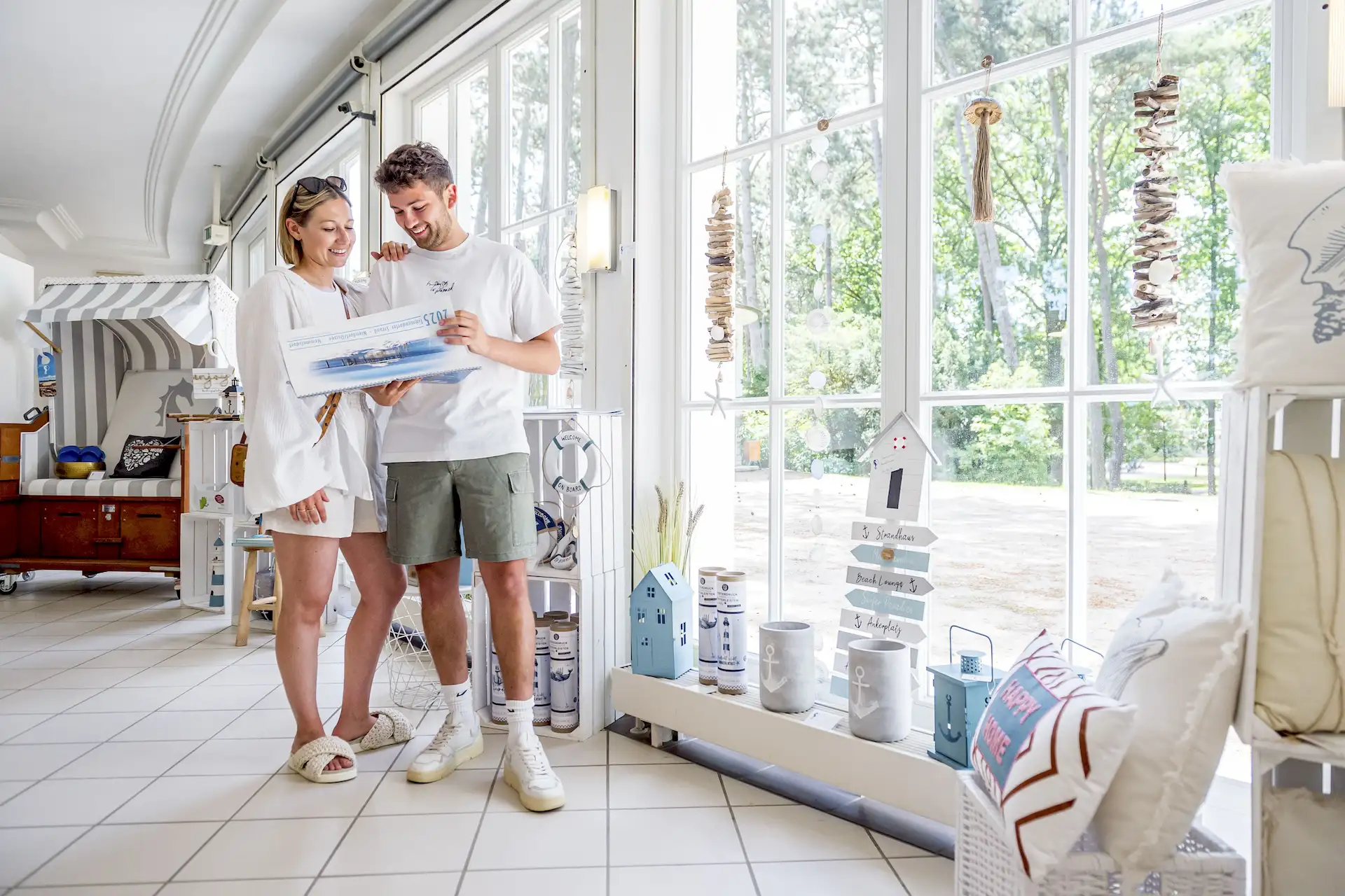 Ein Mann steht mit einem Wandkalender in der Hand in einem Laden für Dekoartikel und eine Frau schaut ihm über die Schulter.