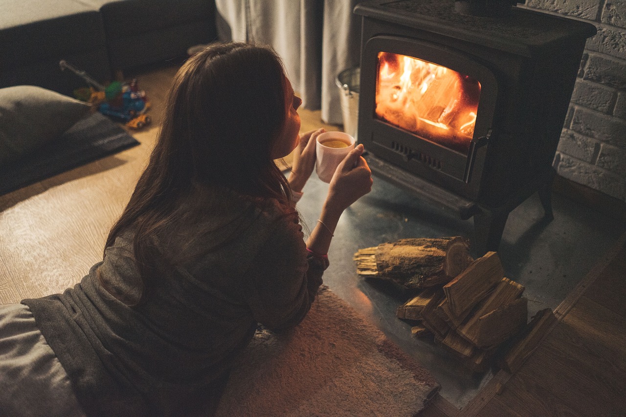 Paar sitzt auf dem Sofa vor dem brennenden Kamin