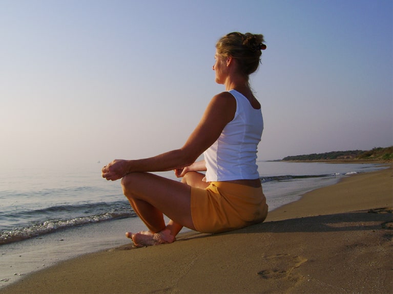 Frau meditiert am Ostseestrand