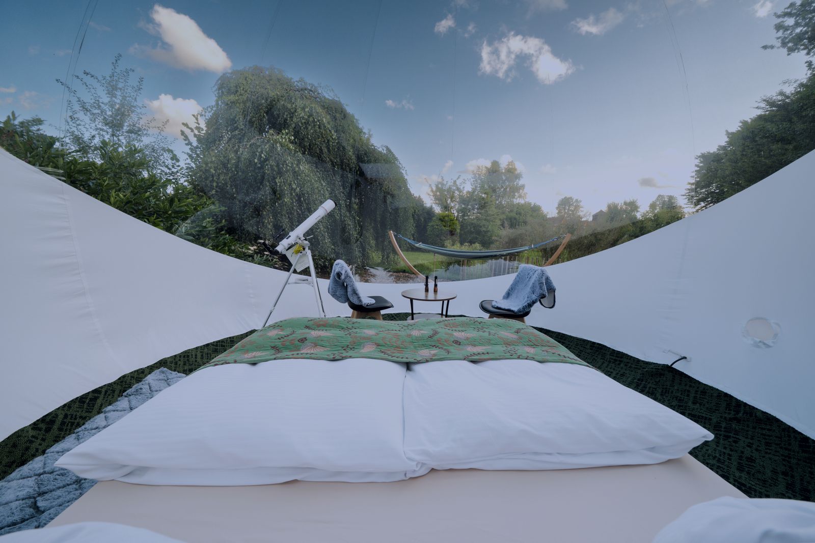 Doppelbett unter der transparenten Kuppel des Bubble Tents mit Blick in den Himmel