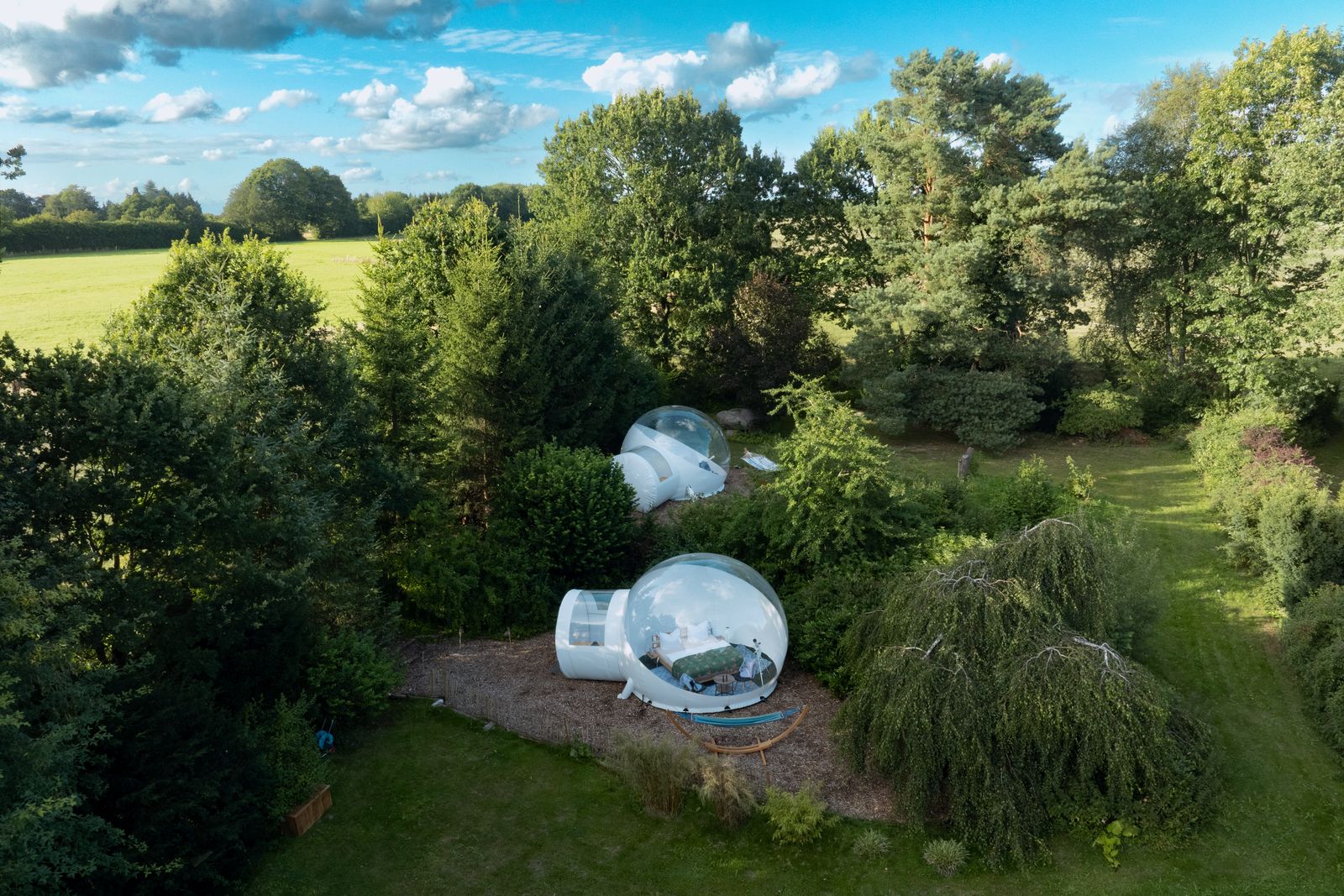 Luftaufnahme: beide Bubble Tents auf dem Grundstück, dahinter offene Felder